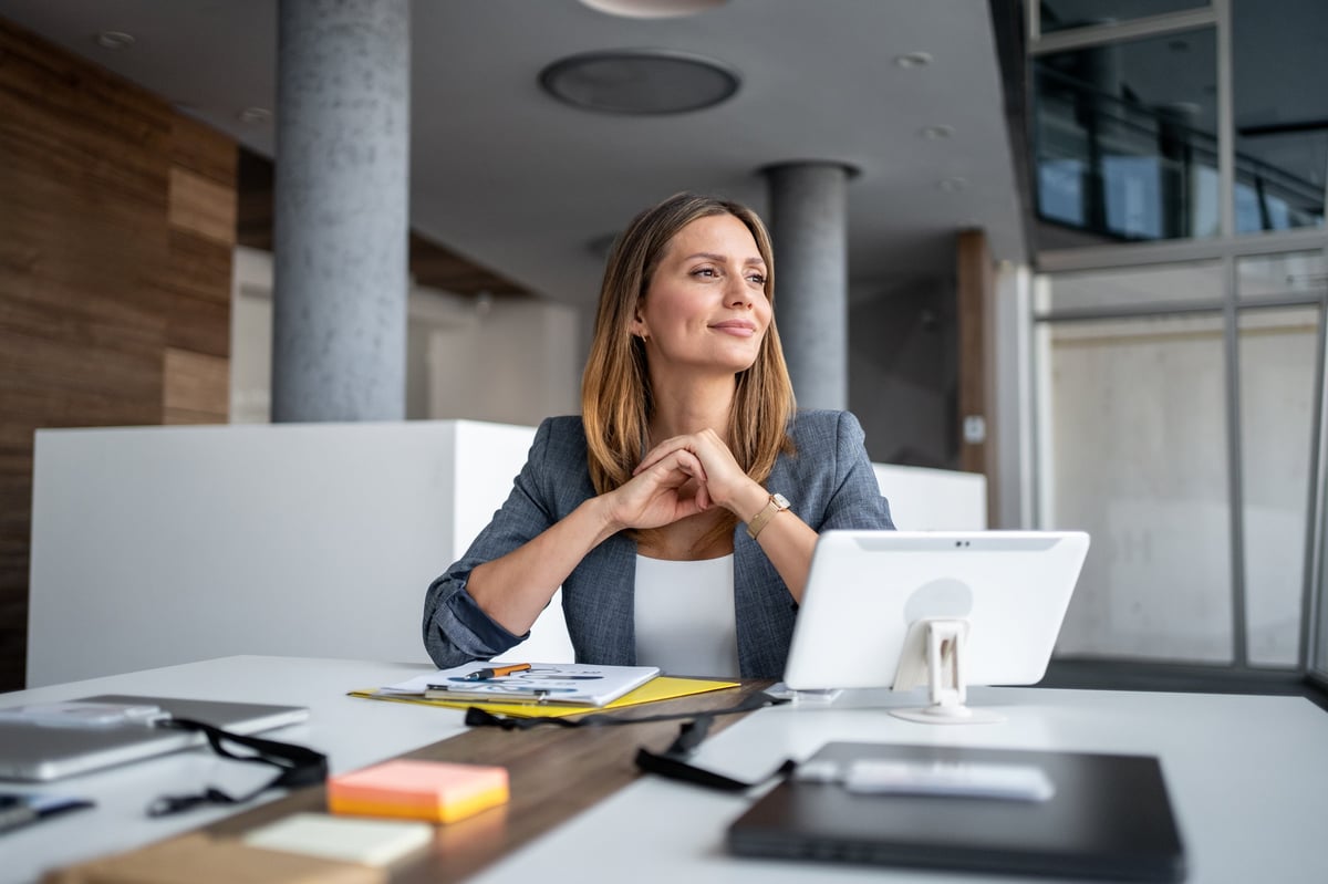 Woman at a modern desk smiling thoughtfully while planning her next steps