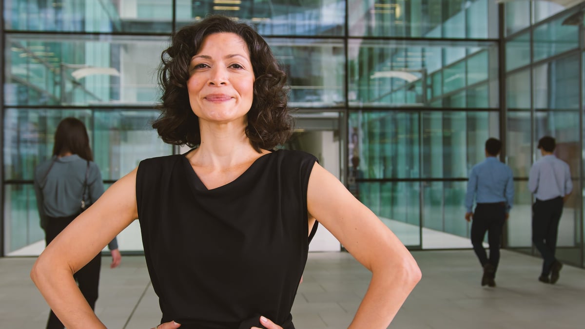 Smiling woman standing confidently with hands on hips in a bright modern space