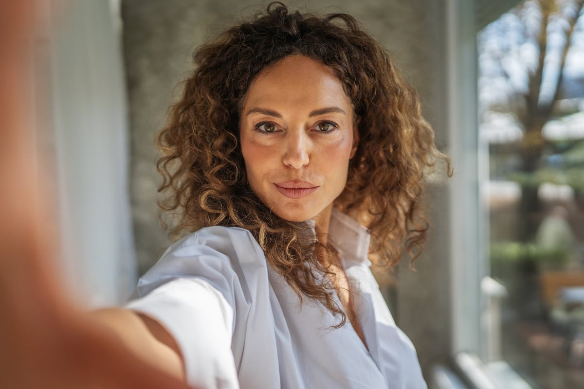 Woman with natural curly hair taking a confident self-portrait in natural light