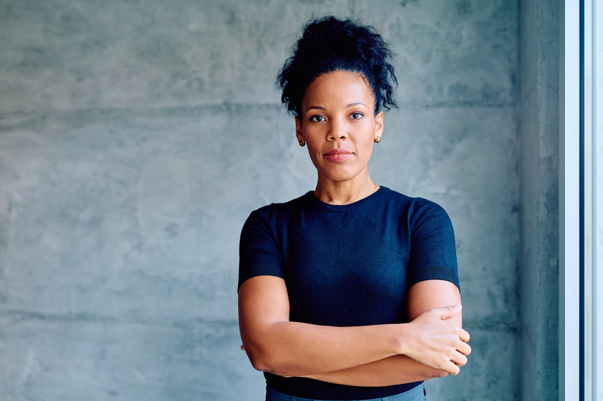 Portrait of a professional woman with a determined, warm expression in a modern workspace